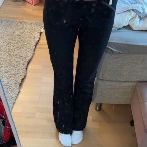 Svarta kostymbyxor med knappar - Snygga svarta kostymbyxor byxor med låg midja och knappar framtill. Väldigt strechiga och Perfekta för en stilren look. Passformen är tight och materialet ser ut att vara bekvämt.