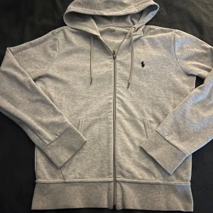 Grå hoodie från Polo Ralph Lauren - Säljer en stilren grå hoodie från Polo Ralph Lauren. 100% äkta finns även qr kod Scan | Skick 9/10 | Storlek: 170 Nypris: ca 2500kr | Färg: grå | Frakt: PostNord. Pris är inte hugget i sten.