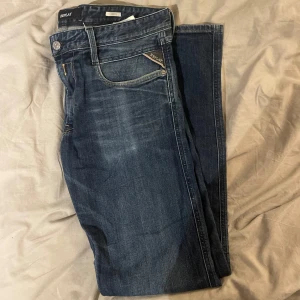 Blå jeans från Replay - Riktigt feta blåa jeans från Replay i modellen Anbass, de har en klassisk femficksdesign och diskreta slitningar. Perfekta för en avslappnad stil. Storleken är 34/32. Vid frågor eller funderingar så är de bara att höra av sig!