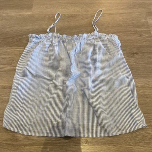 Blå- och vitrandig linnetopp från H&M - Säljer en söt blå- och vitrandig linnetopp från H&M. Toppen har smala axelband och en luftig passform, perfekt för varma sommardagar. Knappt använd så i väldigt fint skick!😊