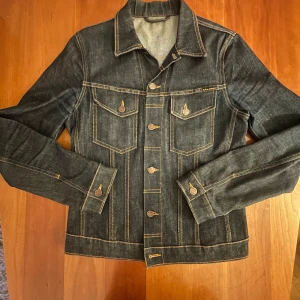 Nudie Jeans Jeansjacka  - Nudie Jeans Jeansjacka (PERRY) i mörk denim. Jackan är i ett mycket bra skick (se bild) och är perfekt nu till våren. Nypris ligger på runt 3000kr! Är även öppen för förhandling! Tveka inte på att höra av dig vid eventuella frågor!