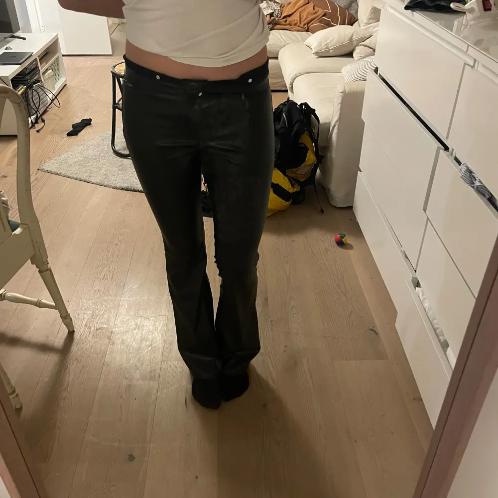 Snygga svarta skinnbyxor med hög midja och tight passform. Perfekta för en stilren look. Byxorna har en klassisk design med dragkedja och knappar framtill. Skriv gärna vid flera bilder eller frågor.. Farkut & Housut.