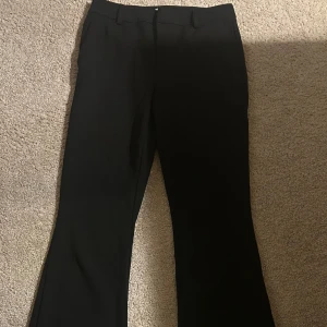 Svarta kostymbyxor från ONLY - Snygga svarta kostymbyxor från ONLY med en klassisk bootcut-stil. Perfekta för en stilren look. Byxorna har en smidig dragkedja och knappar framtill. Finns inte att köpa längre. Perfekt passform! 