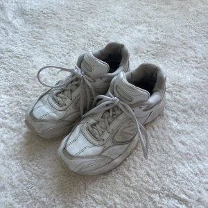 Vita sneakers från New Balance - Säljer ett par klassiska vita sneakers från New Balance med snörning. Perfekt bekväma för vardagsbruk.