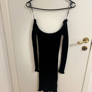 Svart offshoulder långärmad klänning - Snygg svart offshoulder klänning med lång ärm och offshoulder-design. Perfekt för en stilren look. Klänningen har en tight passform som framhäver figuren. 