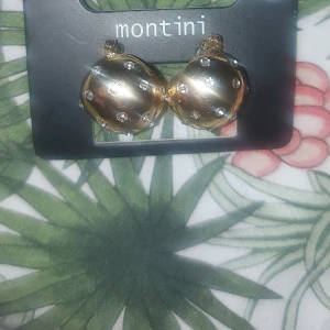 Guldiga örhängen från Montini - Snygga guldiga örhängen från Montini med glittriga detaljer. Perfekta för att ge en touch av glamour till din outfit. Kommer i en praktisk förpackning från Ur & Penn.
