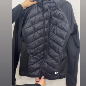 Svart pufferjacka med dragkedja - Snygg svart pufferjacka med dragkedja framtill. Jackan har en quiltad design och långa ärmar, perfekt för kyligare dagar. Den har en sportig look och är lätt att matcha med olika outfits.använd 1 gång 