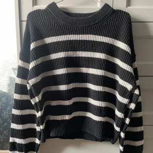 Svart och vit randig stickad tröja - Säljer en snygg svart och vit randig stickad tröja med långa ärmar. Tröjan har en ribbad struktur och en avslappnad passform som är perfekt för kyligare dagar. 