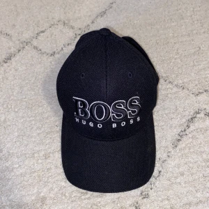 Svart keps från Hugo Boss - Hugo Boss keps i mycket bra skick. Nästan aldrig använd