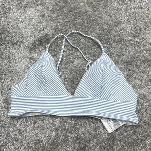 Randig bikiniöverdel - Snygg bikiniöverdel med smala blå och vita ränder. Den har en enkel design med smala axelband och en bekväm passform. Perfekt för en dag på stranden eller vid poolen.