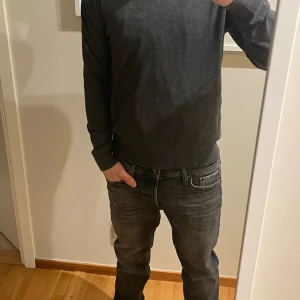 Mörkgrå tröja med dragkedja - Säljer en stilren mörkgrå tröja med dragkedja vid halsen. Tröjan har långa ärmar och en klassisk passform, perfekt för kyligare dagar.