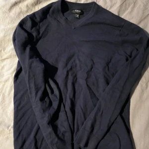 Mörkblå tröja från Smog - Säljer en stilren mörkblå tröja från Smog i slim fit. Tröjan har en v-ringad hals och långa ärmar, perfekt för en elegant och avslappnad look. Passar bra till både jeans och chinos.