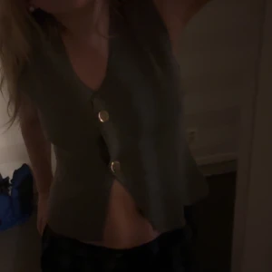 Grå väst med knappar - Snygg grå väst med v-ringning och knappar framtill. Perfekt för att lägga till en stilren touch till din outfit.