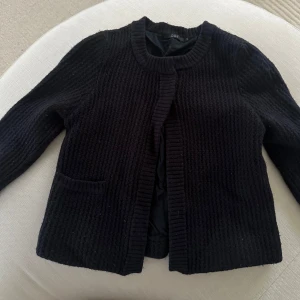 Mörkblå stickad kofta från COS. 100% ull - Säljer en mörkblå stickad kofta från COS. Koftan har en rund halsringning. 100% ull. 