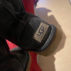 Mörkblå UGG boots - Säljer ett par klassiska mörkblå UGG boots i mocka med en robust gummisula. Perfekta för kyligare väder och ger en mysig känsla. UGG-loggan syns tydligt på hälen.  Säljer pgr av för små stolek 37