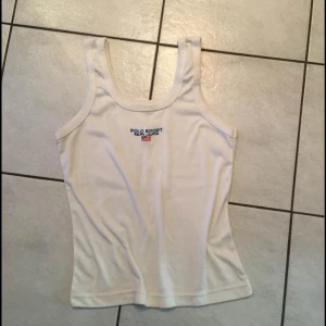 Vit linnetopp från Polo Sport - Säljer en stilren vit linnetopp från Polo Sport med logga på bröstet. Perfekt för varma dagar eller som ett basplagg i garderoben.