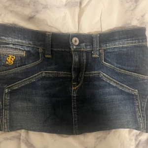 Mini skirt från free soul - Snygg mörkblå jeanskjol från free soul med klassisk femficksdesign och guldfärgade sömmar. OBS den är sydd själv som man kan se på sista bilden. Kjolen är för kort för mig därför väljer jag att sälja den.