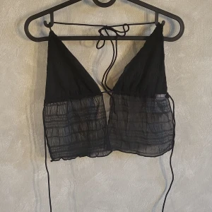 Svart topp från Shein - Snygg svart topp från Shein med knytband i ryggen. Perfekt för en trendig look med triangelformade kupor och lätt material.