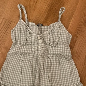 Rutig linnetopp från Brandy Melville - Söt rutig linnetopp från Brandy Melville med knappar framtill och smockdetalj i ryggen. Toppen har smala axelband och volangkant nedtill. Perfekt för en avslappnad sommarlook! Den är så så gullig och i jätte bra skick! Skriv om frågor osv. 💕💕💕 pris kan diskuteras 