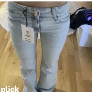 Ljusblå bootcut jeans från Pull&Bear - Säljer ett par ljusblå bootcut jeans från Pull&Bear. De har en låg midja med dubbla knappar i midjan. Super fina 
