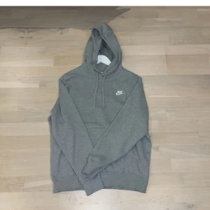 Grå hoodie från Nike - Säljer en klassisk grå hoodie från Nike med justerbar huva och ribbade muddar. Perfekt för en avslappnad stil. Den har en liten Nike-logga på bröstet. 9/10 i skick då den är som ny, använd fåtal gånger. 