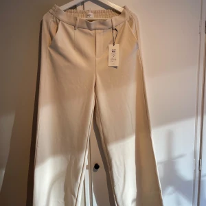 Beige byxor från Object - Snygga beige byxor från Object med elastisk midja och raka ben. Perfekta för en stilren look. Byxorna har en avslappnad passform och är tillverkade i ett mjukt material.