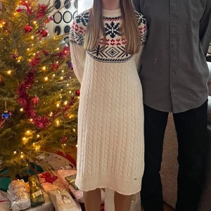 Vit stickad klänning från Holly & Whyte - Mysig vit stickad klänning från Holly & Whyte med ett klassiskt mönster i rött och marinblått. Klänningen har långa ärmar och en rund halsringning, perfekt för kyliga dagar. Jag tycker att klänningen är väldigt skön, jag är 160cm på bilden och både armarna och längden satt perfekt. Allmänt väldigt skön och "välarbetad". En perfekt julklänning i bra kvalitet, använd 3 gånger men den är i mycket bra skick. Säljer pågrund av att den tyvärr är för liten. Skriv vid frågor.✨️🤍