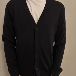 Svart kofta från Riley - Snygg svart kofta från Riley med knappar framtill. Storlek S. Modellen på bilden är 181 cm lång.