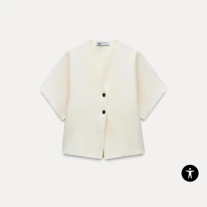 Vit kortärmad kofta från Zara - Säljer en stilren vit kofta från Zara med korta ärmar och två knappar framtill. Säljer pågrund av att den ej kommer till användning, prislappen kvar, alltså inga defekter!! 