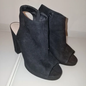 Svarta klackskor från H&M - Snygga svarta klackskor från H&M med öppen tå och dragkedja på sidan. Perfekta för en stilren look. Garderobsrensning så kika gärna på övriga auktioner.