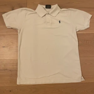 Vit kortärmad pikétröja från Ralph Lauren - Snygg vit pikétröja från Ralph Lauren med klassisk krage och korta ärmar. Tröjan har en broderad logotyp i mörkblått på bröstet. Perfekt för en stilren och avslappnad look. Obs storlek M men passar S. Om du har någon fråga eller fundering hör av dig mvh Levi!