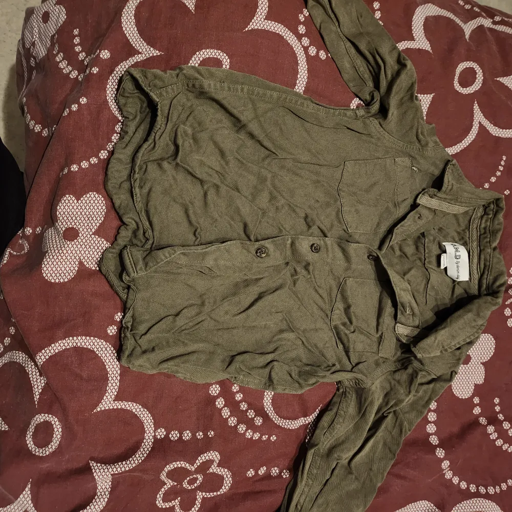 Säljer en olivgrön henley-skjorta från H&M. Skjortan har långa ärmar och knappar framtill. Perfekt för en avslappnad stil. Fin att ha till festligt tillfälle :). Paidat.