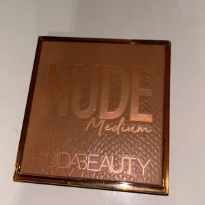 Nude Medium ögonskuggspalett från Huda Beauty - Säljer en superfin Nude Medium ögonskuggspalett från Huda Beauty. Den har nio olika nyanser i både matta och skimrande toner, perfekt för både vardag och fest. Färgerna går i rosa, bruna och guldiga nyanser. Paletten är knappt använd och i toppskick!