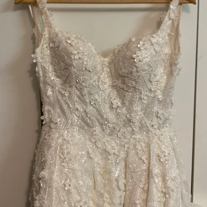 Brudklänning - Säljer min brudklänning från märket Sima couture nypris 39.000kr inkl allt (underkjol och brudslöjan). Klänningen är storlek 34 men kan passa 32 och 36.  Jag säljer den inkl under kjolen och brudslöjan som är väldigt lång . Klänningen behöver kemtvätt 