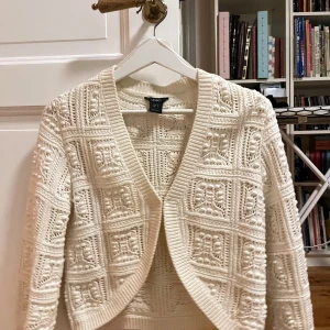 Vit stickad bolero kofta från Lindex - Säljer en superfin vit stickad bolero kofta från Lindex i storlek S. Den har ett snyggt mönster och är perfekt för både vår och höst. Koftan är i mycket bra skick och har en öppen design framtill. Perfekt att slänga över en topp för en mysig look! 🤍