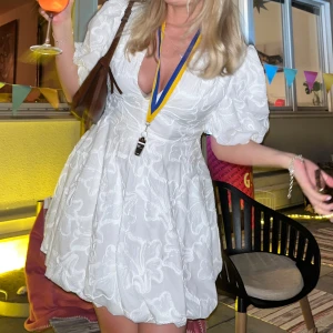 Vit kortklänning med puffärmar - Säljer en superfin vit kortklänning med puffiga kortärmar och v-ringning från Zara. Perfekt för sommarens fester eller studentfiranden. Endast använd en gång på min studentkväll och det finns inga tecken på användning. Nypris 700kr