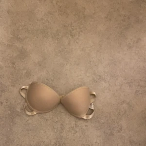 Beige bh med hjärtmönster - Säljer en söt beige bh i storlek M med ett gulligt hjärtmönster på insidan. Den har justerbara axelband och är i mycket bra skick. Perfekt för vardagsbruk eller speciella tillfällen. Bekväm och stilren design!
