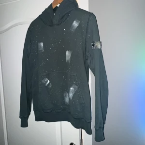  Stone Island hoodie - Säljer en cool grön hoodie från Stone Island. Den har ett unikt mönster med vita stänk och penseldrag, vilket ger den en konstnärlig touch. Perfekt för höst och vinter!