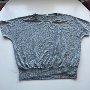 Grå tröja från Stories - Säljer en supermjuk och bekväm grå tröja från Stories. Perfekt för en avslappnad look med sin loose passform och kortärmade design. Materialet känns lätt och luftigt, vilket gör den idealisk för både vår och sommar. Ett måste i garderoben för dig som älskar enkel stil!