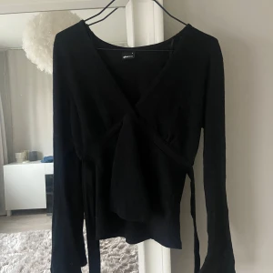 Svart omlottopp från Gina Tricot - Säljer den trendiga tröjan/blusen från gina❣️Storlek s men skulle säga att den har samma passform som xs