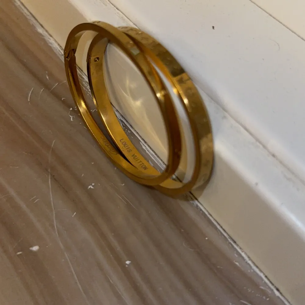 Säljer ett stilrent guldarmband med ingraverade symboler runt om. Armbandet är i mycket bra skick och har en elegant design som passar perfekt för både vardag och fest. Det är ett tidlöst smycke som enkelt kan kombineras med andra accessoarer.. Accessoarer.