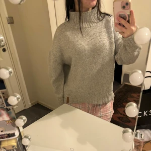 Grå stickad polotröja - Mysig grå stickad polotröja perfekt för kyliga dagar. Den har en hög krage och långa ärmar, vilket gör den superbekväm och varm. Tröjan är i bra skick och passar perfekt för både höst och vinter. Enkelt att matcha med olika outfits!