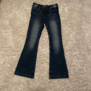 Blå bootcut jeans från h&m - Säljer ett par snygga blå bootcut jeans i bra skick. De har en klassisk femficksdesign och en lätt slitning för en cool look. Perfekta för både vardag och fest! Passar till allt från sneakers till klackar. De är mid waist. 