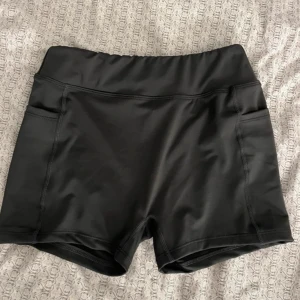 Svarta träningsshorts med fickor - Ett par mörkgråa träningsshorts med fickor på båda sidorna. Stora för sin storlek, passar den som är storlek 32 och 34. Aldrig andvända! 