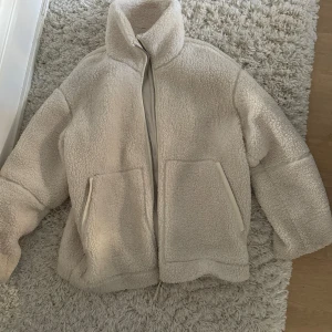 Beige teddyjacka - Mysig beige teddyjacka i mycket bra skick. Perfekt för kyliga höst- och vinterdagar. Jackan har en dragkedja framtill och två stora fickor. Den är långärmad och har en normal passform. Superbekväm och trendig!