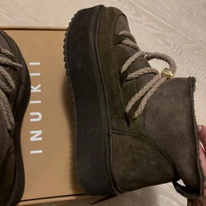 Inuikii - Säljer ett par snygga bruna boots från Inuikii i mocka. De har en rejäl platåsula och grova snören som ger en cool look. Perfekta för höst och vinter, håller dig varm och stilren. Använda en vintersäsong men i mycket bra skick! 