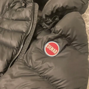 Svart dunjacka från Colmar säljes eller bytes  - Säljer en svart dunjacka från Colmar i mycket bra skick. Den är perfekt för vintern med sin varma och puffiga design. Jackan har en dragkedja framtill och en hög krage för extra skydd mot kylan. Den är långärmad och har en snygg logga på ärmen. Passar perfekt för kalla dagar. Den är i storlek xxs-xs  men jag skulle personligen säga att den är mke större i storleken typ 160-168 ❤️ Pris kan diskuteras! Kan tänka mig byten 