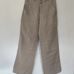 Beige linnebyxor från BZR i strl 31, 100% linen-hør  - Säljer ett par snygga beige linnebyxor från BZR i storlek 31. Byxorna har en avslappnad wide fit och är perfekta för vår och sommar. De har knappar framtill och en stilren design som passar både till vardags och fest. Superbekväma och luftiga!