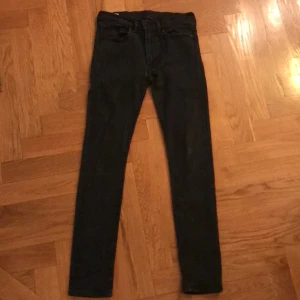 Svarta jeans från Levi's - Säljer ett par svarta Levi's jeans i bra skick. De har en slim passform och är perfekta för både vardag och fest. Klassisk design med fem fickor och knappgylf. Passar till alla säsonger och är ett måste i garderoben! Priset kan diskuteras.