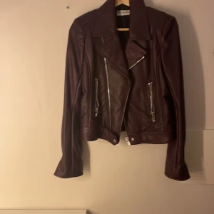 Balenciaga Mörklila läder biker jacket - Säljer en snygg mörklila skinnjacka från Balenciaga i storlek 42 men är liten i storlek. Använd endast 2 gånger och är i nyskick. Jackan har en cool bikerstil med dragkedjor och en asymmetrisk design. Perfekt till höst och vår. Köpt i paris  för ca 20 000kr men säljer för 7000
